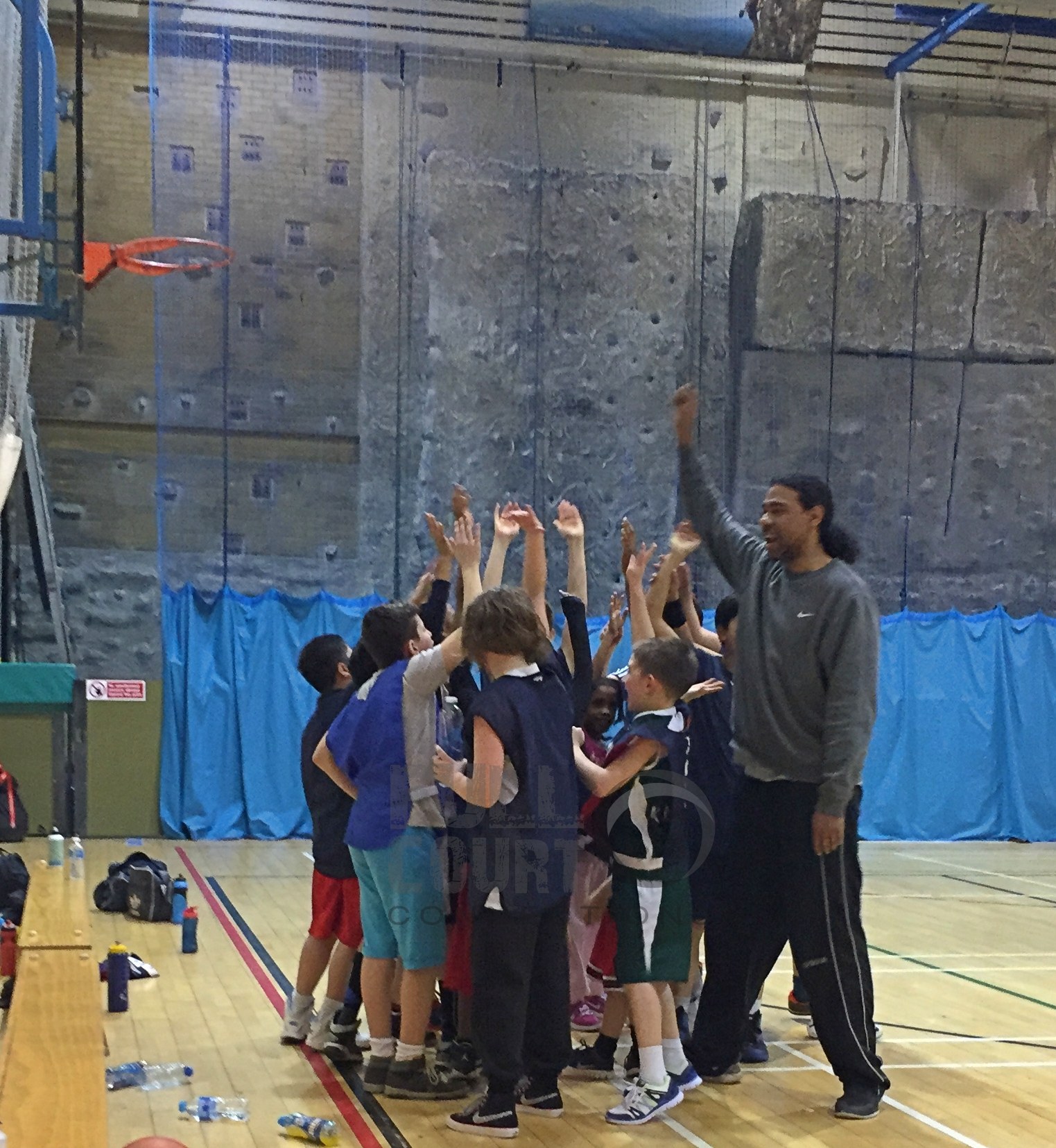 Coach Leon raising his hand with young basketball players during a Full Court Connections session
